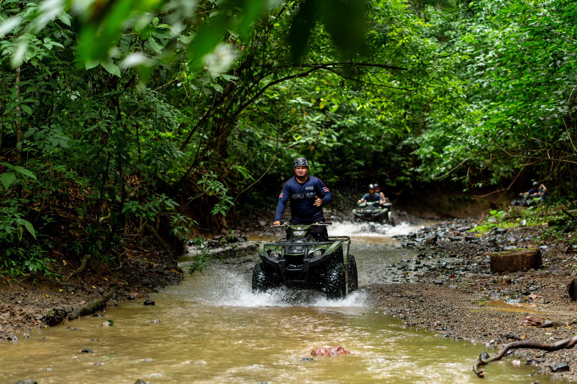 Solo ATV rider crossing a creek deep in the Costa Rica rainforest