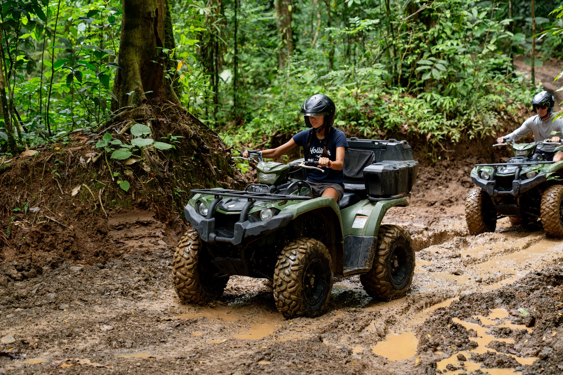 Yamaha ATVs navigating a muddy jungle trail through dense vegetation