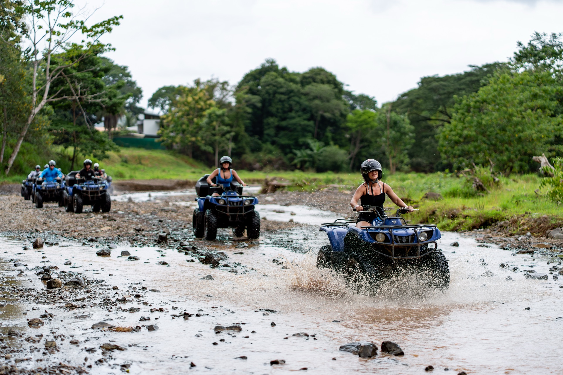 Caravan of ATVs crossing a rocky river on the Costa Rica jungle adventure